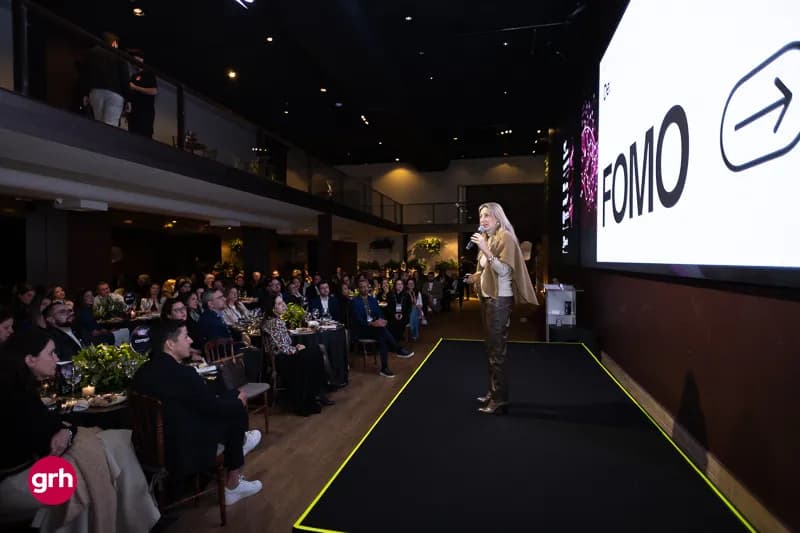 A palestrante Sabina Deweik fala em frente a uma platéia